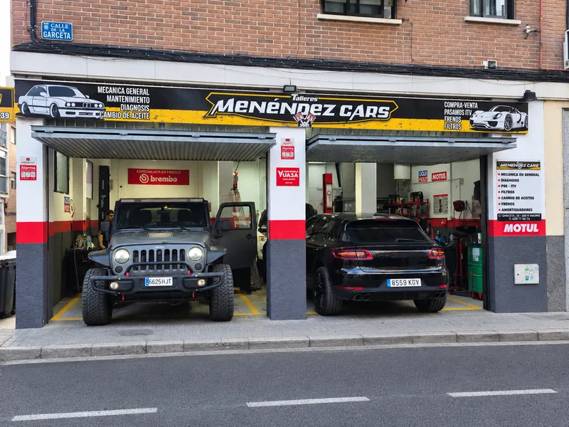 Fachada del taller con un Jeep Wrangler y un Porsche Macan